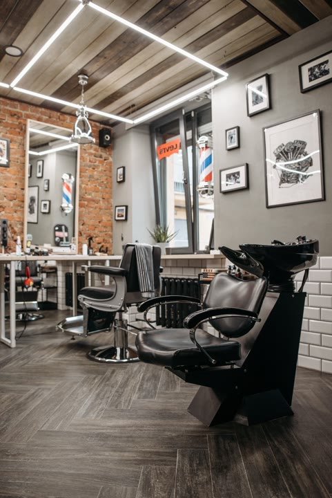 A sleek, modern barbershop interior with exposed brick and styling chairs